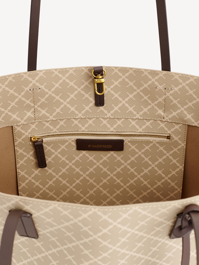 By Malene Birger Abigail veske i beige Signature Flower-print, med skinndetaljer og mørke stropper.