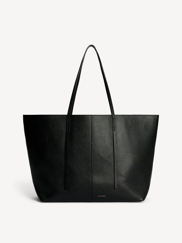 By Malene Birger Abilla skinnveske i sort kuskinn, med strukturert overflate, en romslig størrelse og to skinnreimer for lukking.