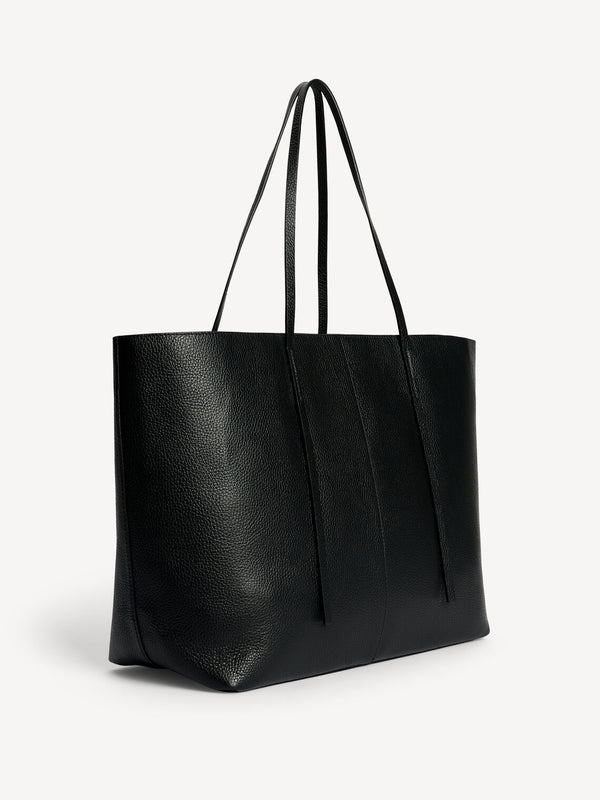 By Malene Birger Abilla skinnveske i sort kuskinn, med strukturert overflate, en romslig størrelse og to skinnreimer for lukking.