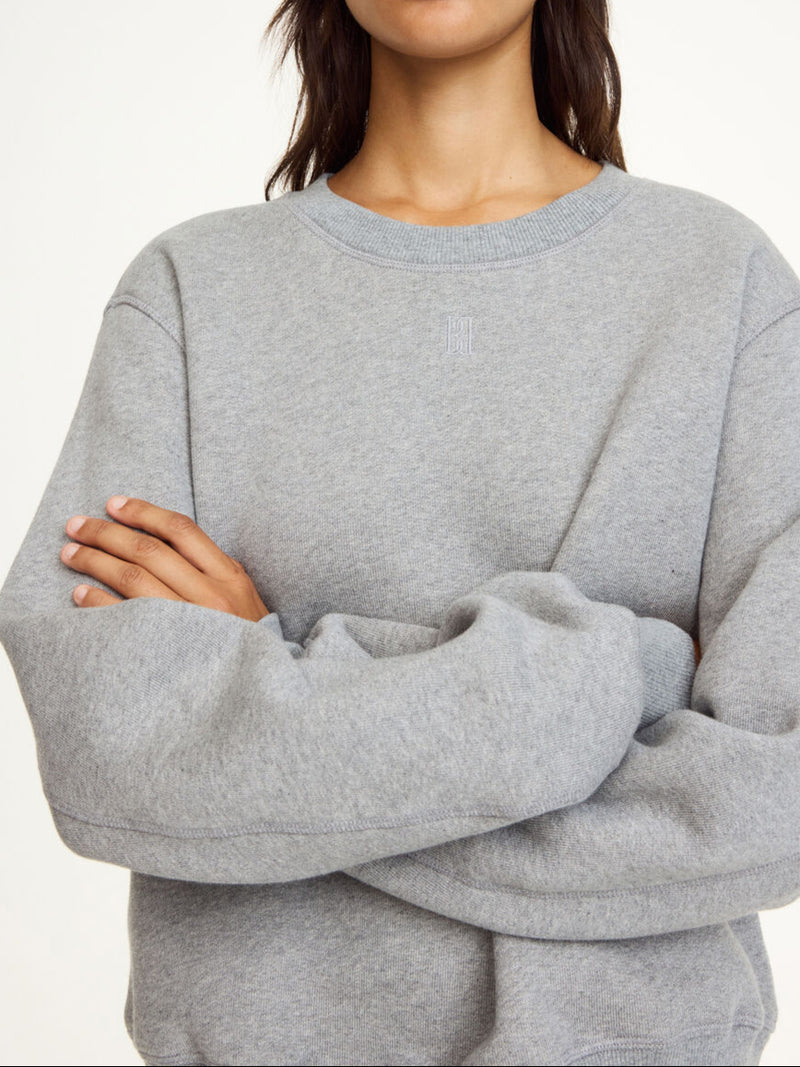 By Malene Birger Apalia genser i grå, laget av 100% organisk bomull, med brodert monogram på brystet og ribbestrikkede avslutninger.