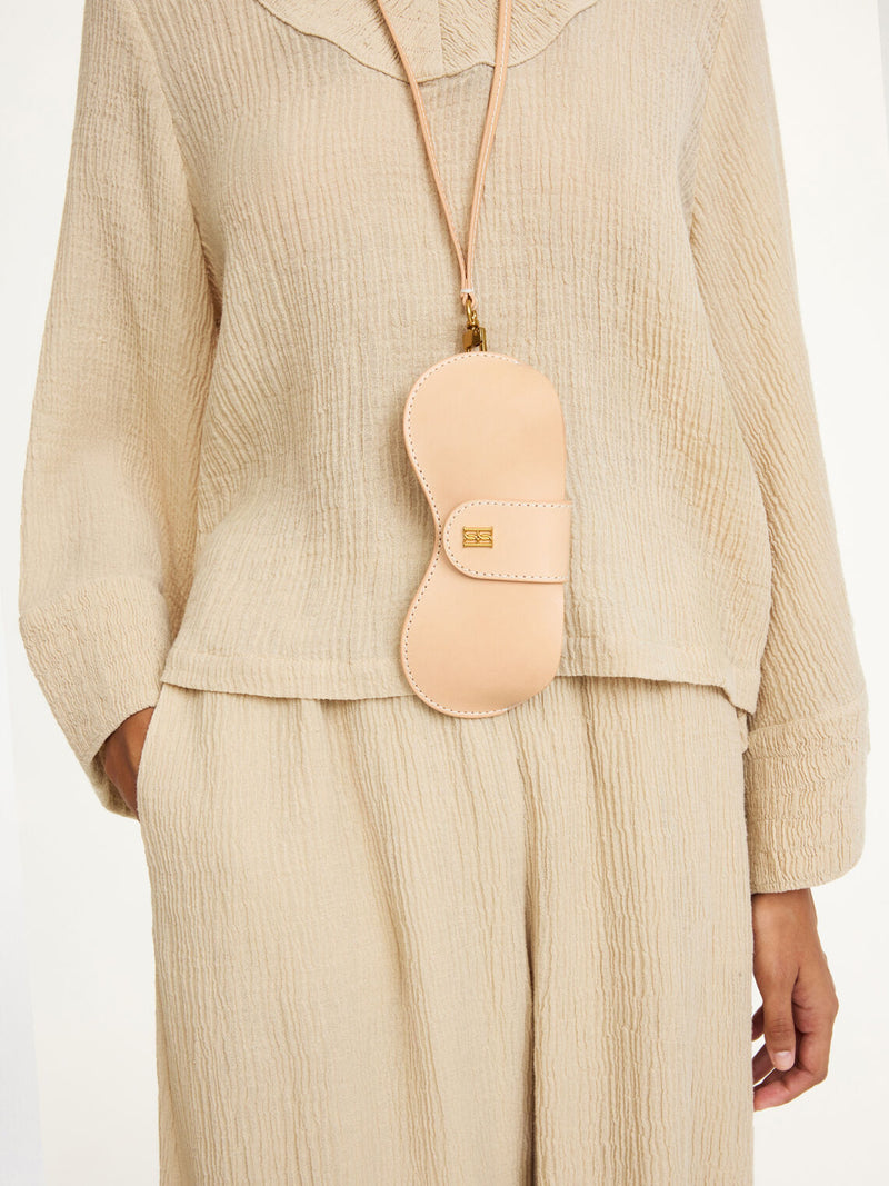 By Malene Birger Aya Sunny solbrilleetui i brun, laget av 100% ubehandlet kuskinn, med monogram-logo og avtagbar reim.