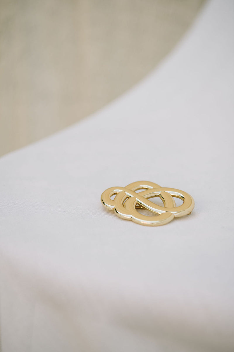 By Malene Birger Broche brosje i gullfarget sink, med myke linjer og et tidløst Swirl-motiv.