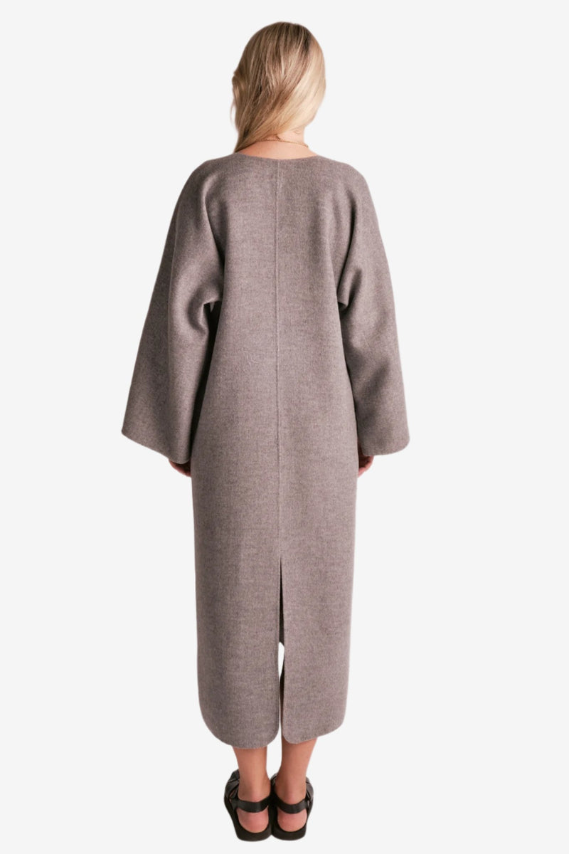 By Malene Birger Cais kjole i grått, laget av 100% ull, med en løs passform, v-utringning og splitt på ermene.