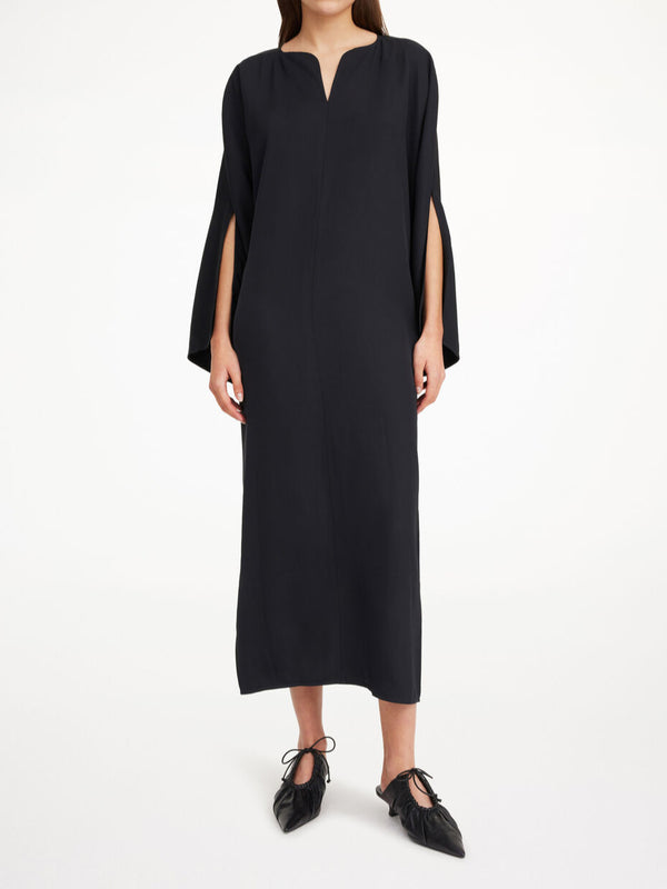 By Malene Birger Cais kjole i sort, laget av lett acetat, med ankel lang lengde, nett v-utringing og splitt på ermene.