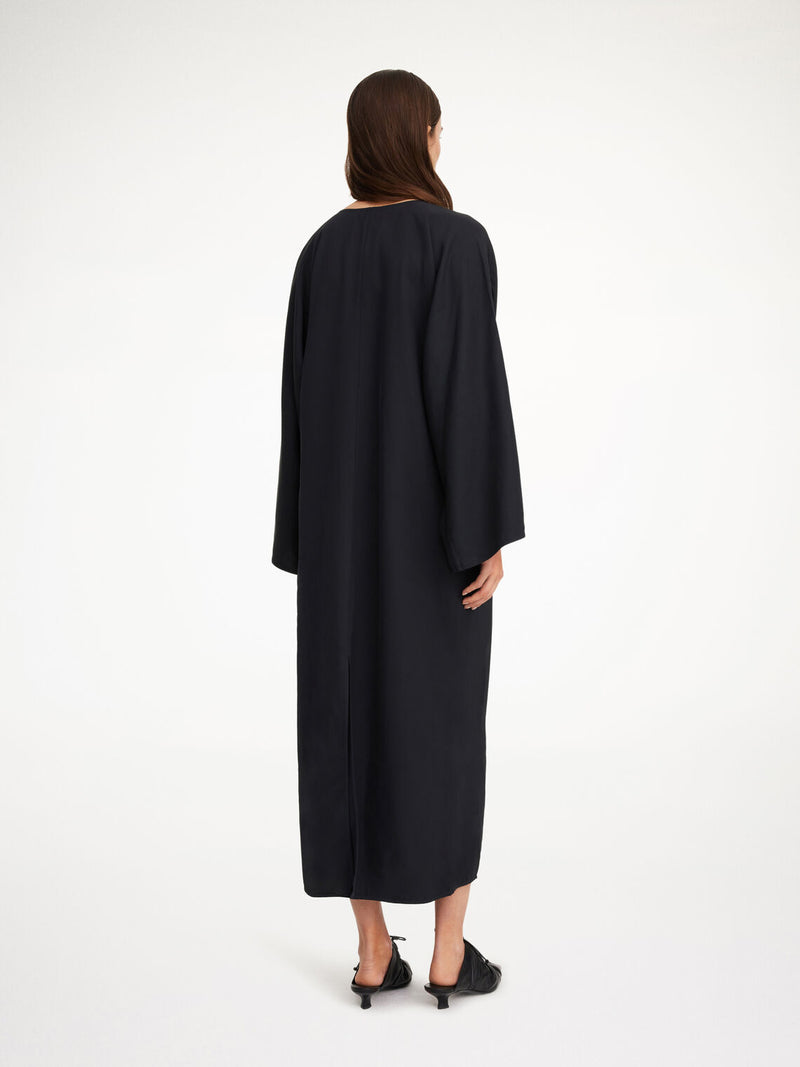 By Malene Birger Cais kjole i sort, laget av lett acetat, med ankel lang lengde, nett v-utringing og splitt på ermene.