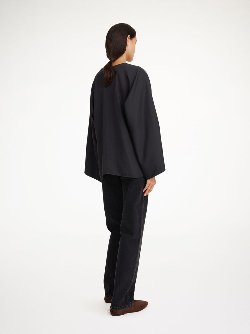 By Malene Birger Calias bluse i sort, laget av 100% acetat med splitt på ermene og v-utringning.