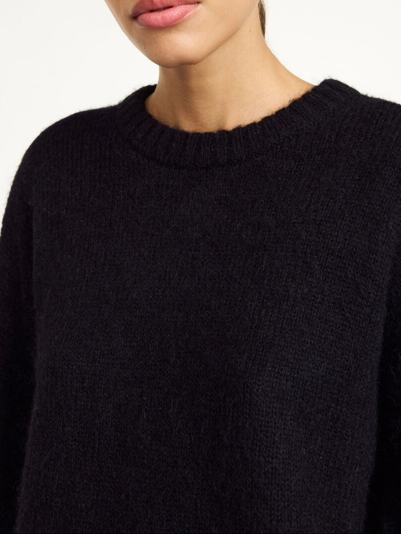 By Malene Birger Cierra genser i sort, med ribbestrikkede detaljer og trompetformede ermer, laget av en blanding av ull, mohair og polyamid.