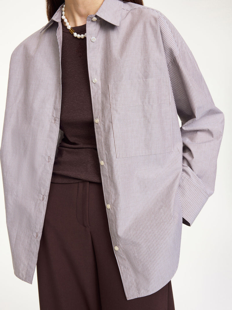 By Malene Birger Derris bomullskjorte i brun- og hvitstripet organisk bomull, med en oversized passform og brystlomme.