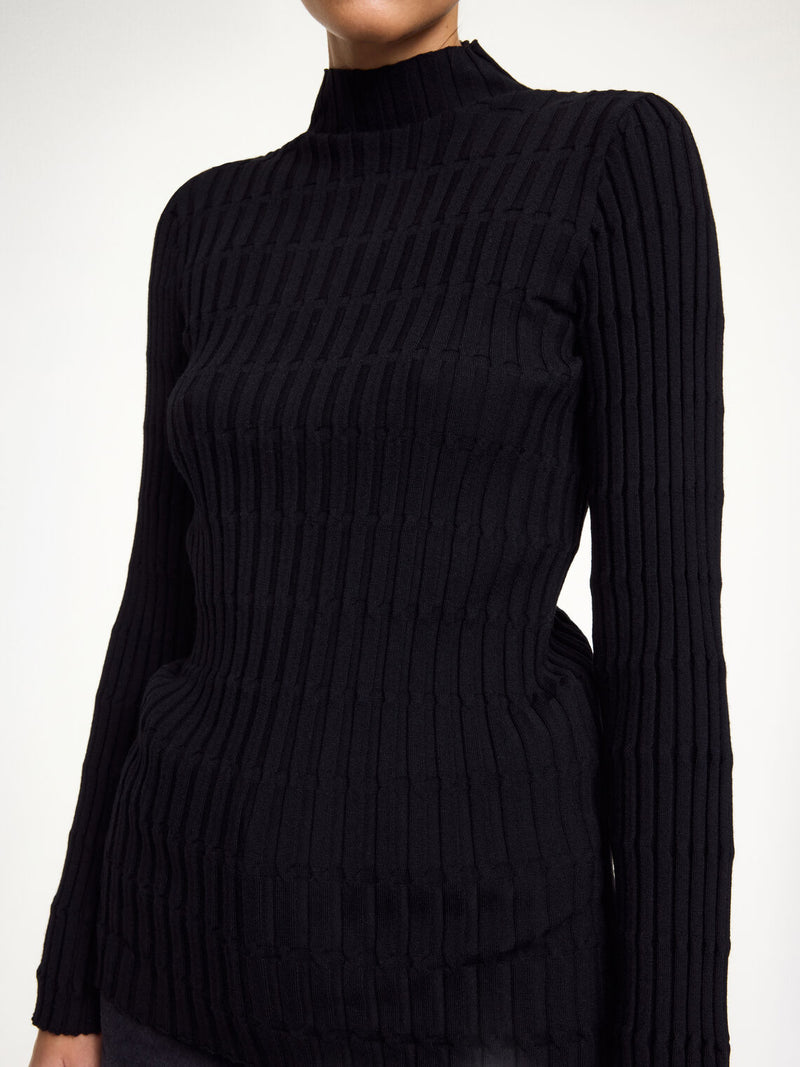 By Malene Birger Inger genser i sort, med nett høy hals og ribbestrikk, laget av merinoull og elastan.