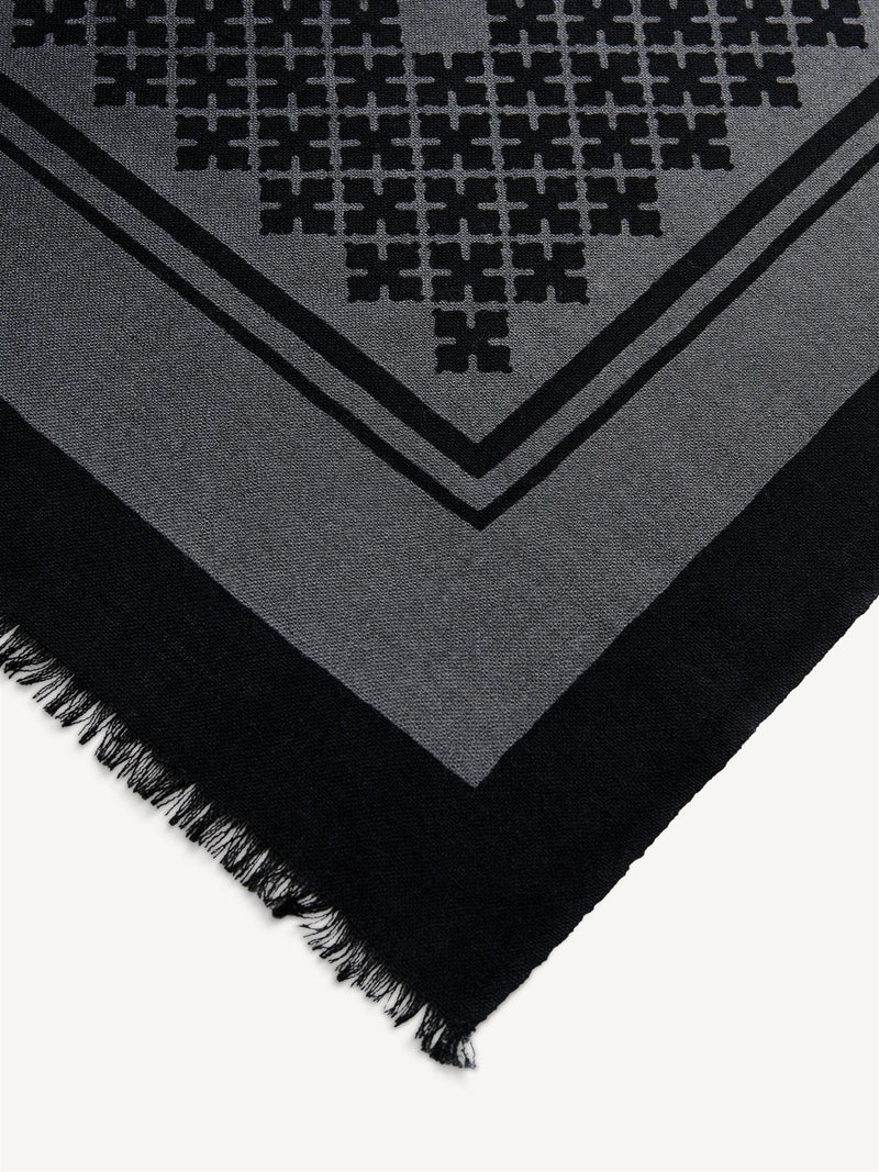 By Malene Birger Julee ullskjerf i mørk grå, med Signature Flower-print og frynser i kantene, laget av 100% ull.