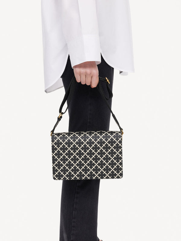 By Malene Birger Loenna crossover-veske i sort polyvinyl chloride, med Signature Flower-mønster, skinndetaljer og justerbar skulderrem.