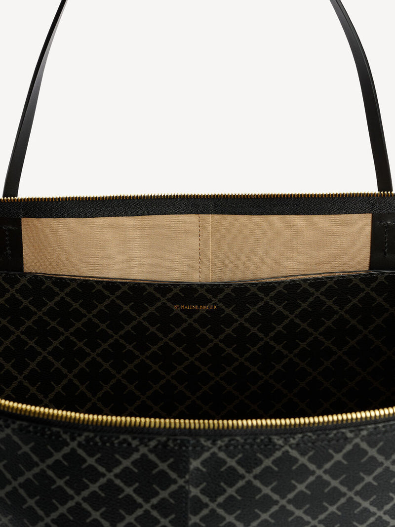 By Malene Birger Luze veske i mørkegrå, med Signature Flower-mønster, glidelåslukking og smale stropper.