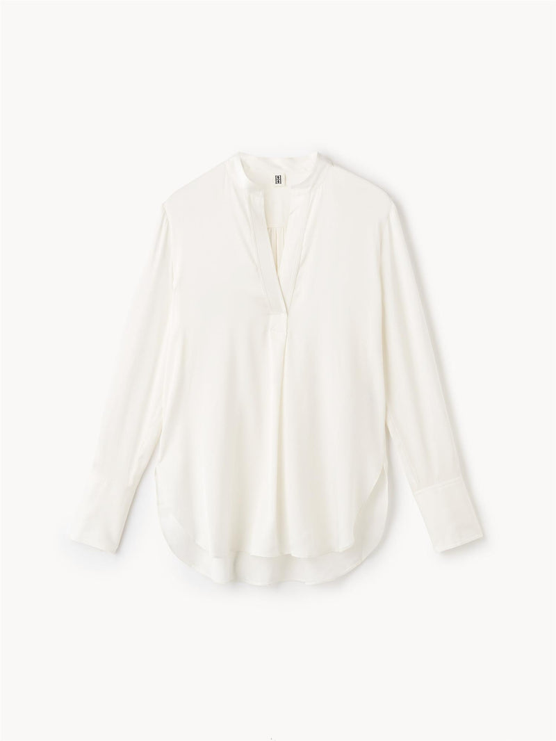 By Malene Birger Mabillon bluse i hvit, laget av en blanding av silke og elastan, med en v-utringning og knapper på mansjettene.