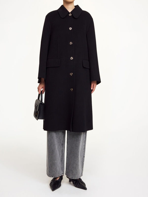 By Malene Birger Maelle kåpe i sort, med en rett passform, buet krage og laget av 100% ull.