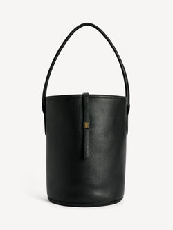 By Malene Birger Maryllon veske i sort skinn, med bøtteform og gullfarget monogram-emblem i front.