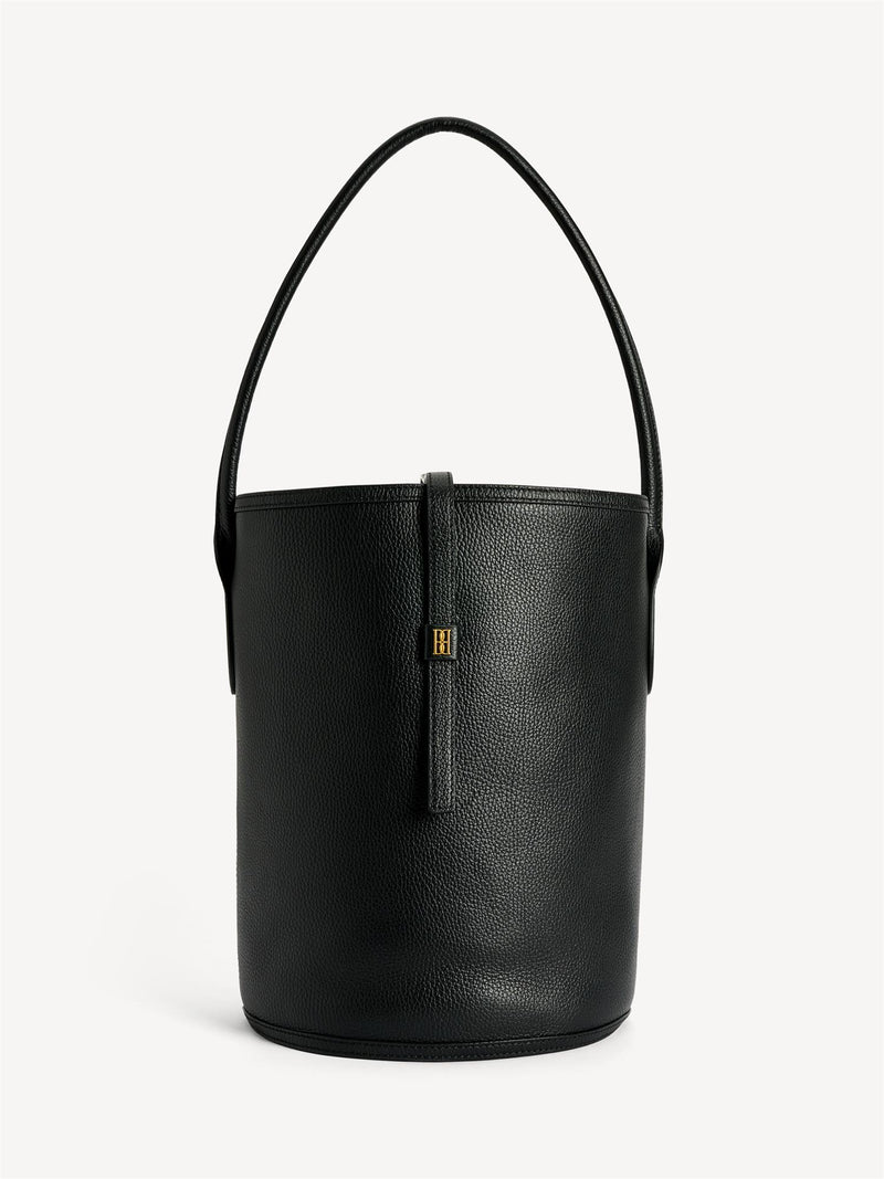 By Malene Birger Maryllon veske i sort skinn, med bøtteform og gullfarget monogram-emblem i front.
