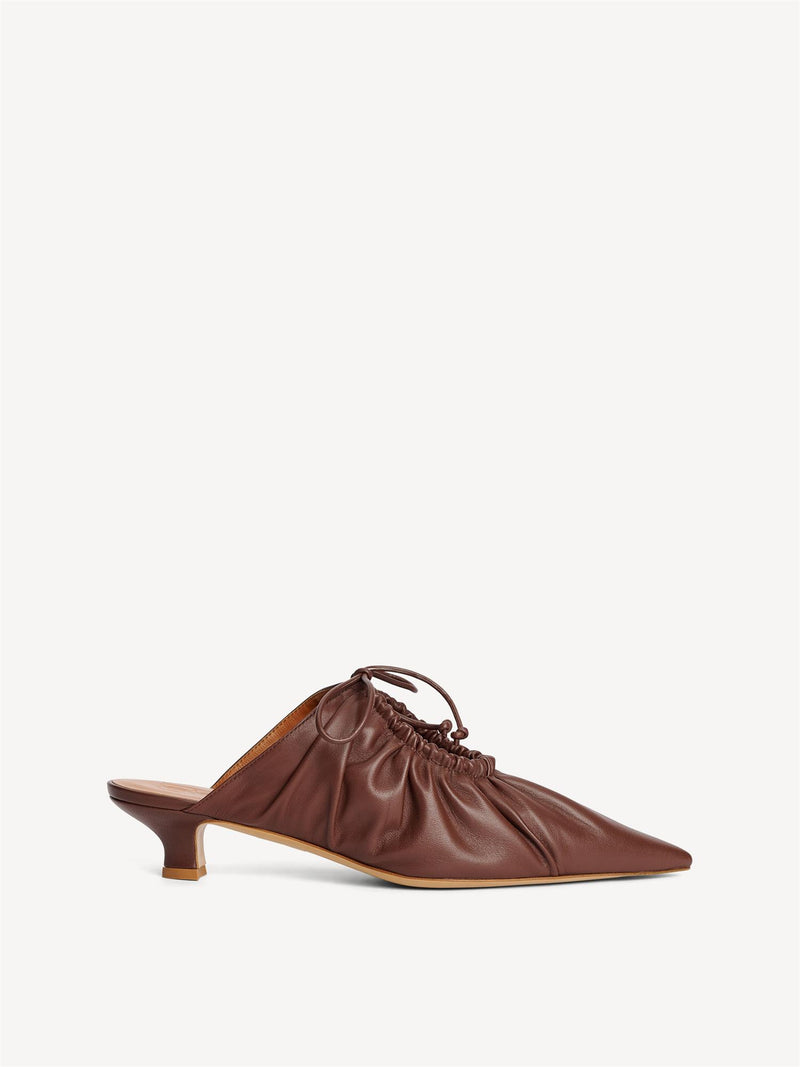 By Malene Birger Masey skinnmules i mørkebrun, laget av geiteskinn, med kitten-heels og en spiss silhuett.