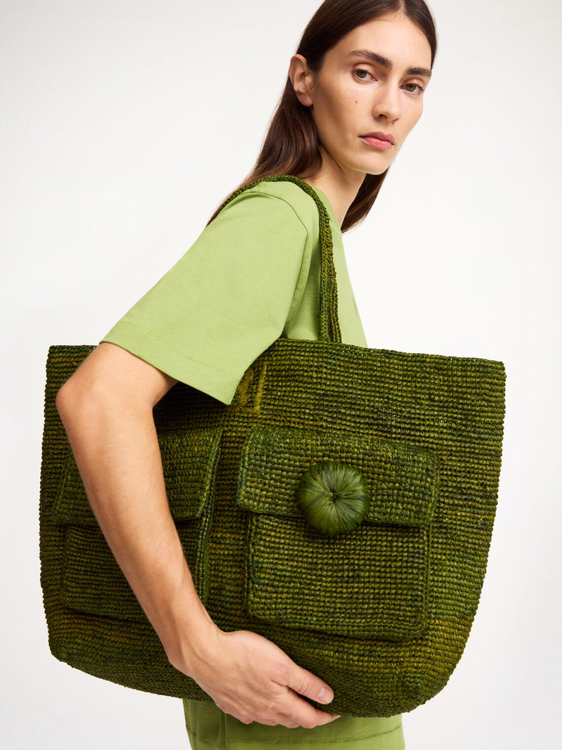 By Malene Birger Miras skulderveske i grønn, laget av 100% strå, med romslig rom, to frontlommer og et brodert monogram.