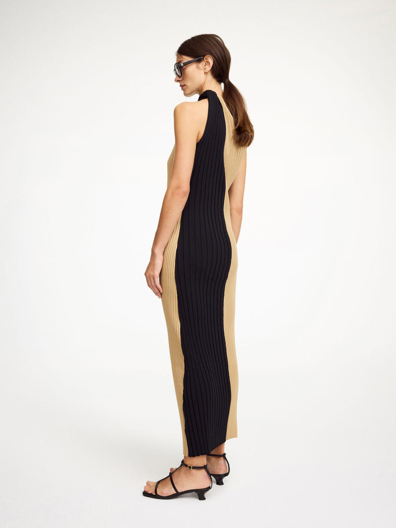 By Malene Birger Noto kjole i sort og beige, med asymmetrisk design over skuldrene og snurret avslutning.
