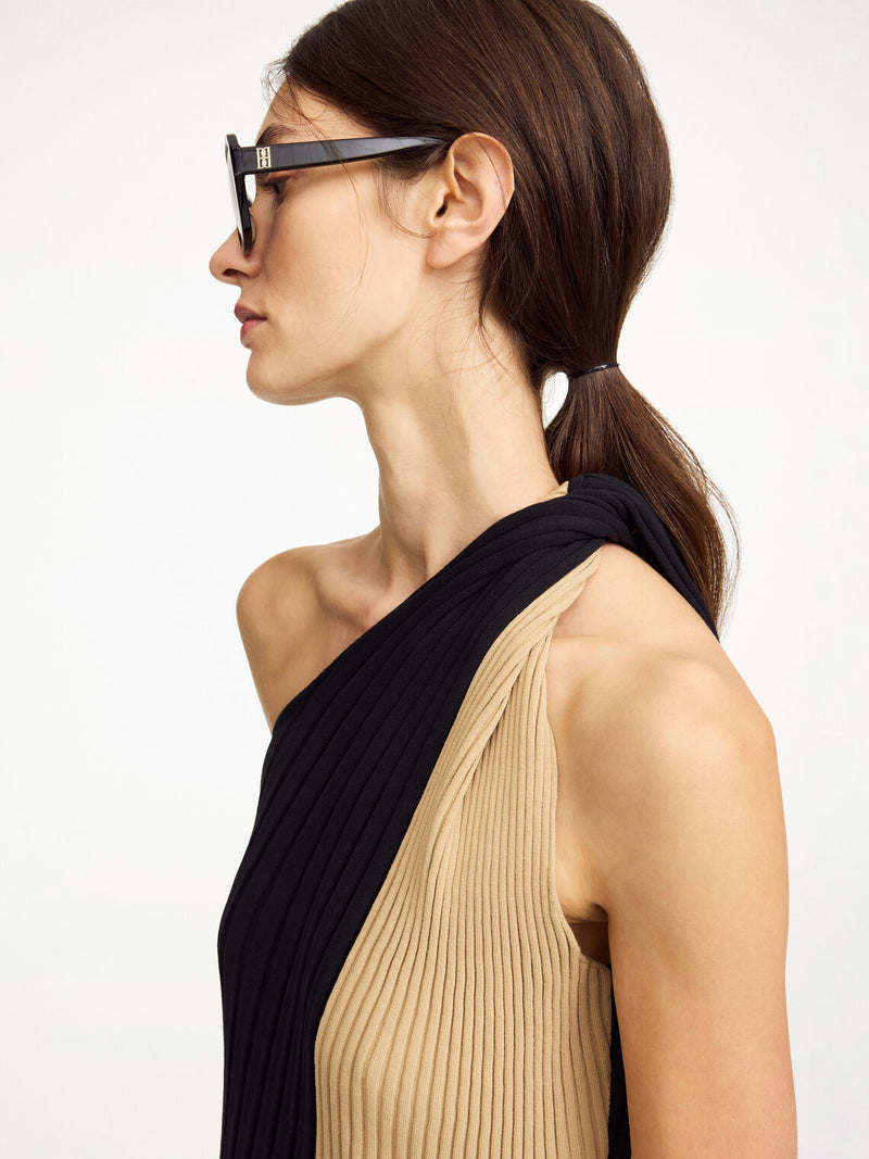 By Malene Birger Noto kjole i sort og beige, med asymmetrisk design over skuldrene og snurret avslutning.
