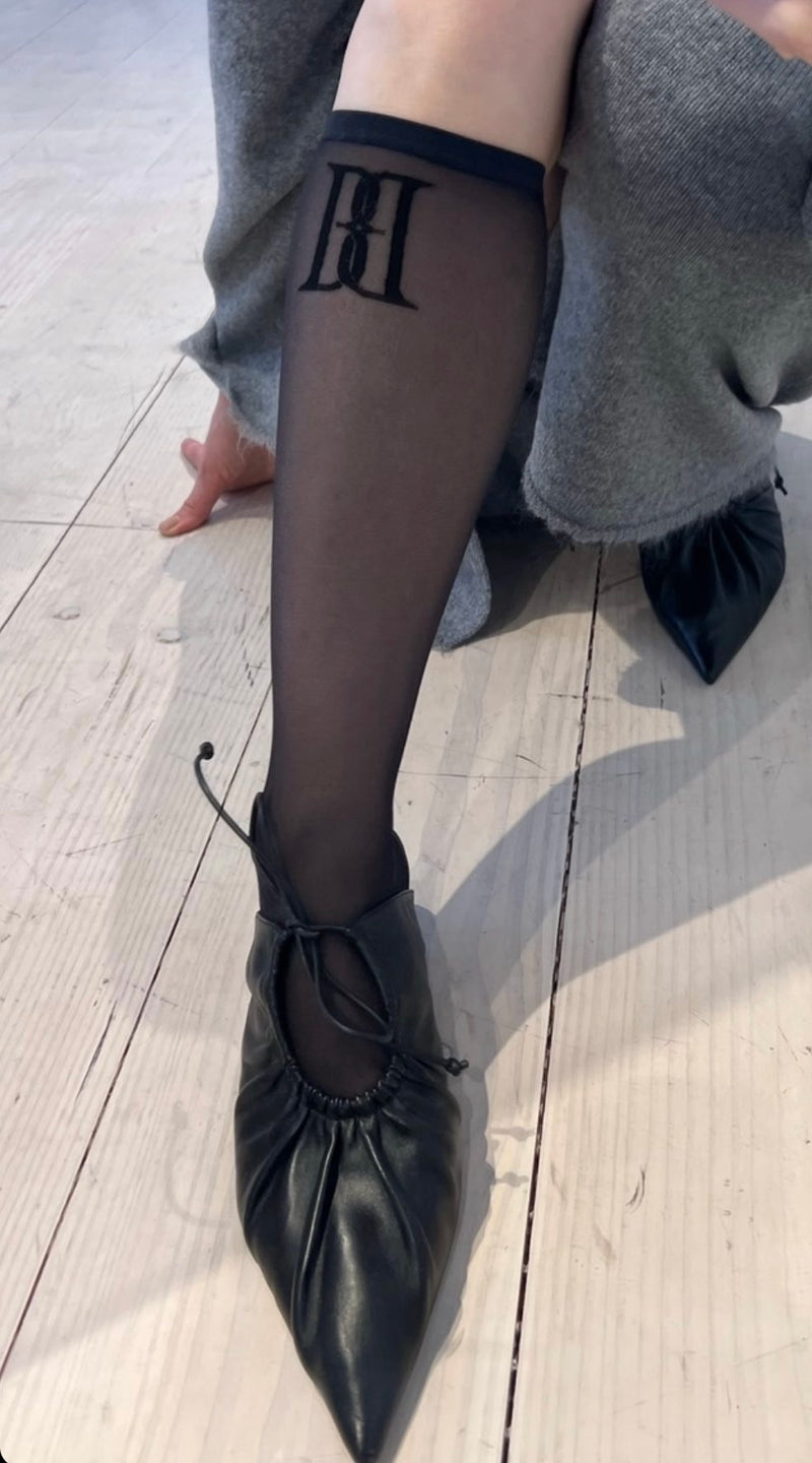 By Malene Birger Nylah nylonstrømper i sort, med brodert emblem i front, laget av resirkulert polyamid og elastan.