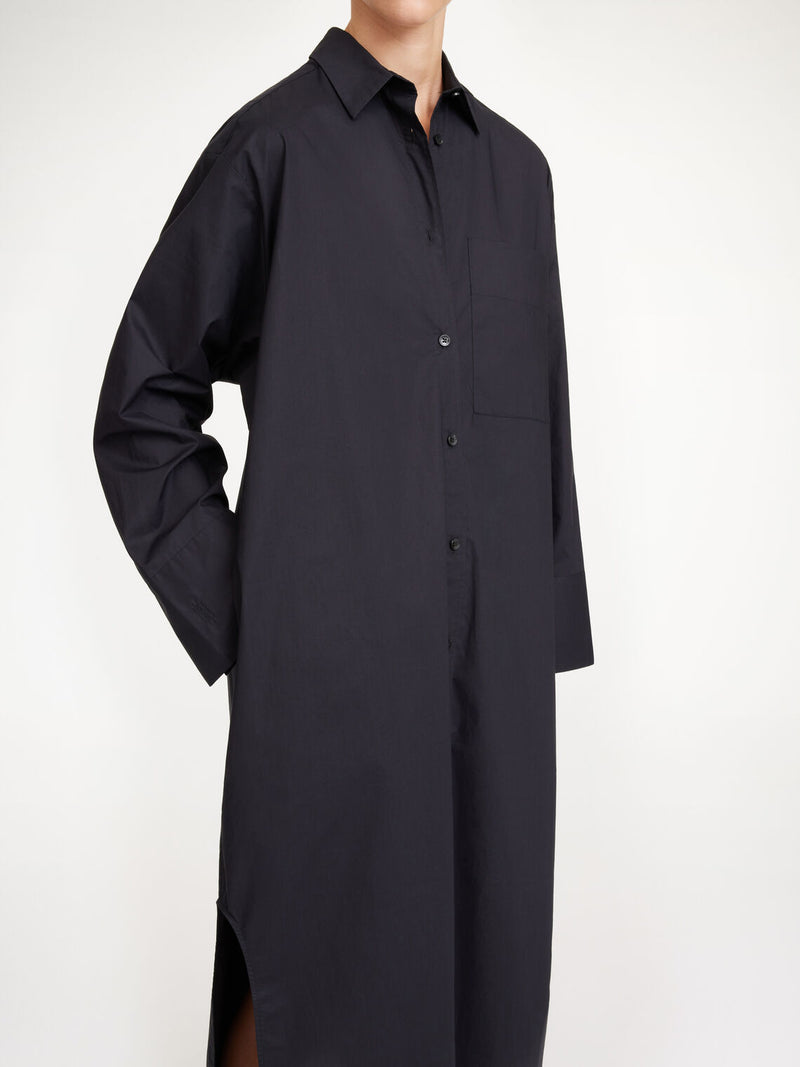 By Malene Birger Perros kjole i sort, laget av organisk bomull, med oversized passform, knapper i front og høy splitt på sidene.