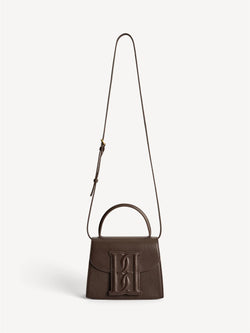 By Malene Birger Ramil veske i strukturert mørkebrun skinn, med monogram-motiv i front og justerbar skulderreim.