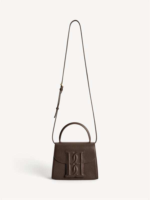 By Malene Birger Ramil veske i strukturert mørkebrun skinn, med monogram-motiv i front og justerbar skulderreim.