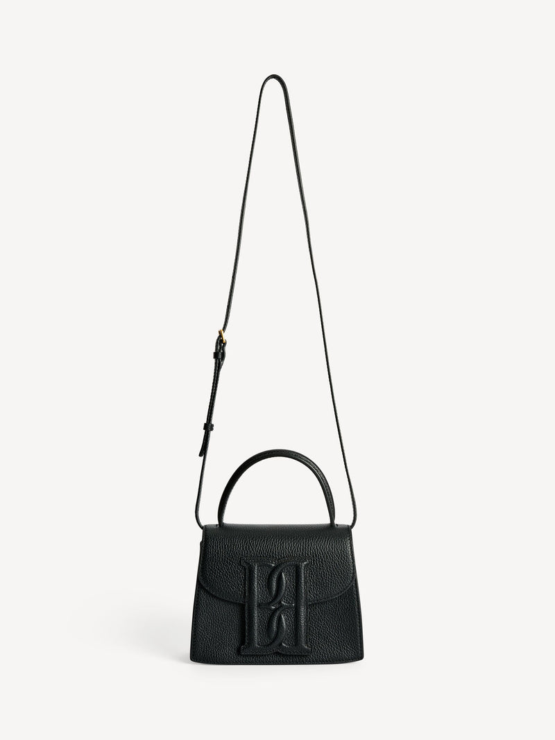 By Malene Birger Ramil veske i strukturert sort skinn, med monogram-motiv i front og justerbar skulderreim.