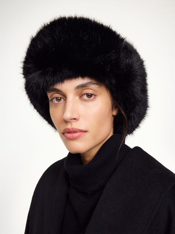 By Malene Birger Rolla lue i sort, laget av 100% bomull og faux fur, med nedbrettbare ører og justerbar knyting under haken.