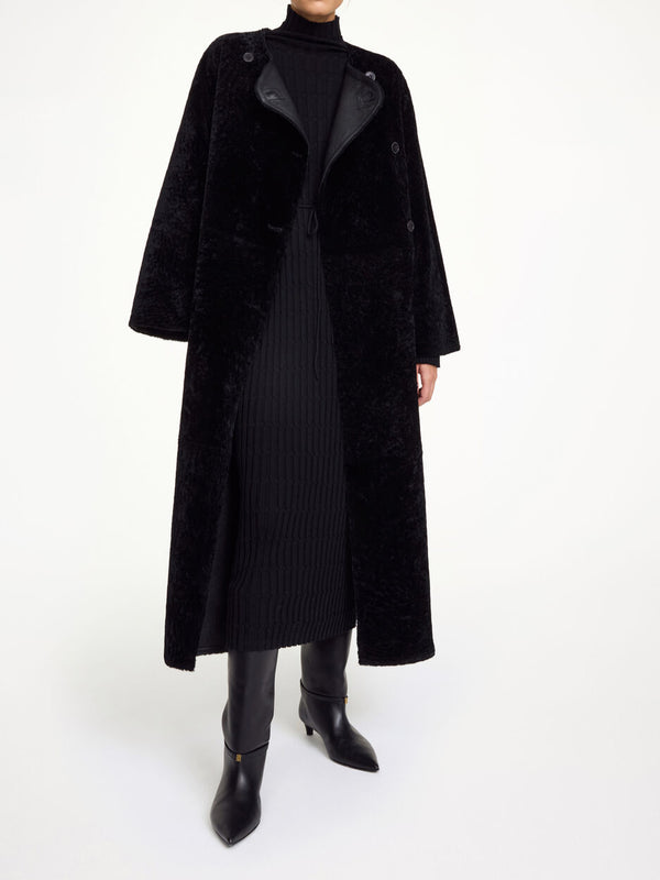 By Malene Birger Sandria lammeskinnskåpe i sort, laget av 100% lammeskinn og pels, med avtagbart belte og maksilengde.