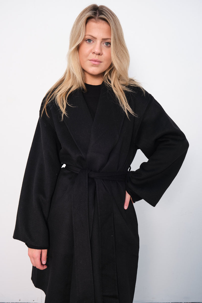 By Malene Birger Trullas kåpe i sort, med en sjal-lignende krage og en rett passform, laget av 100% ull.