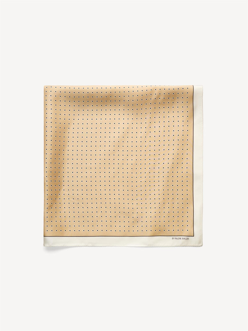 By Malene Birger Velia silkeskjerf i sand, laget av 100% silke med et elegant mønster og et lite logo i hjørnet.