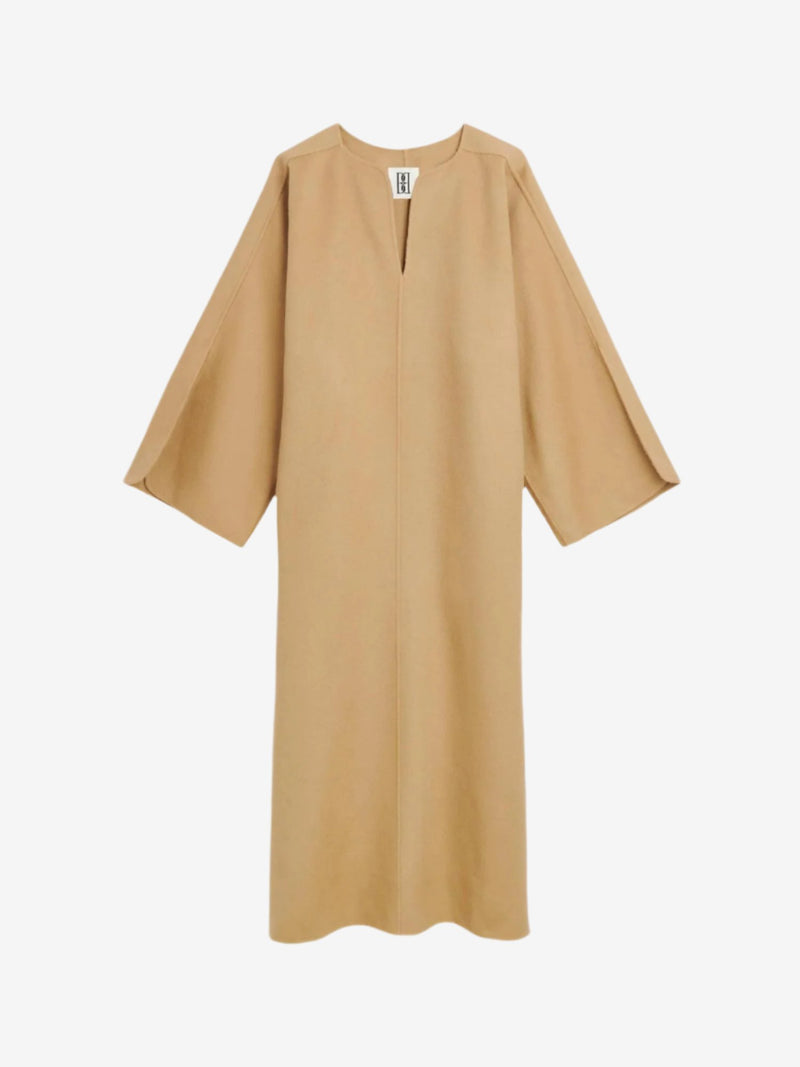 By Malene Birger Cais kjole i beige, laget av 100% ull, med en løs passform, v-utringning og splitt på ermene.