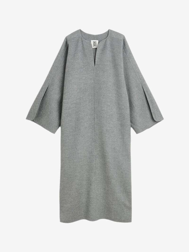 By Malene Birger Cais kjole i grått, laget av 100% ull, med en løs passform, v-utringning og splitt på ermene.