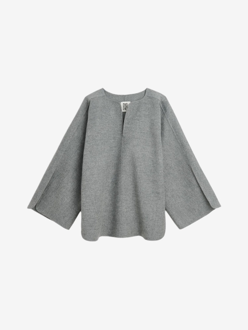 By Malene Birger Calias bluse i grå, laget av 100% ull, med v-utringning og splitt på ermene.